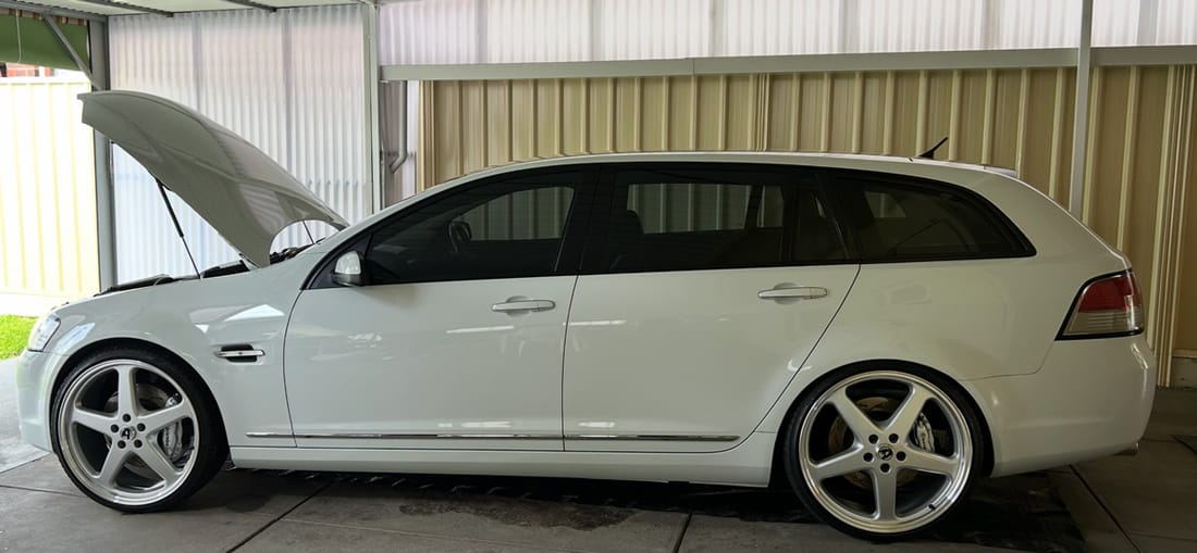 A white Holden Commodore wagon detailed under a carport