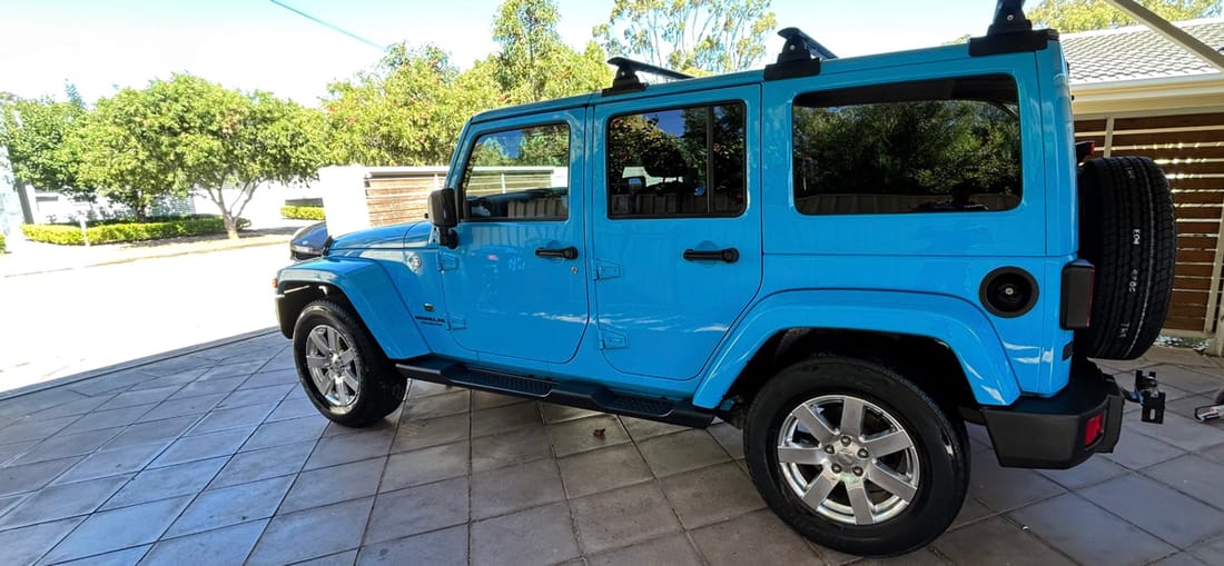 A bright blue Jeep Wrangler gleaming after a detail