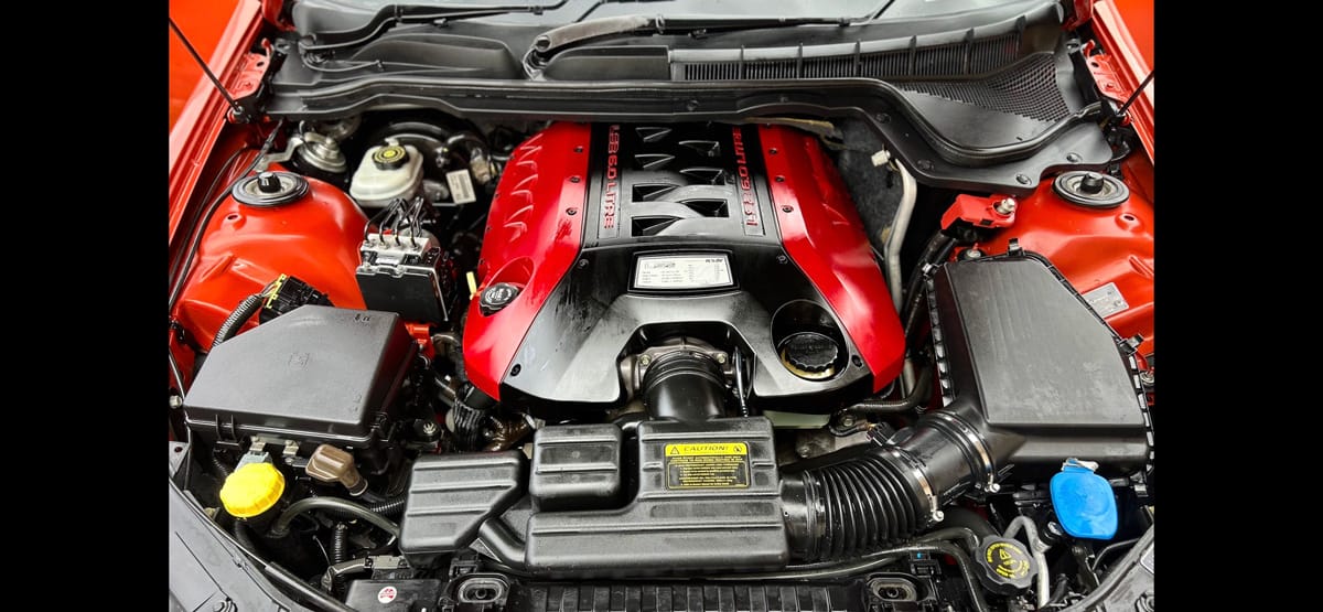 A spotless detailed engine bay with a red engine cover